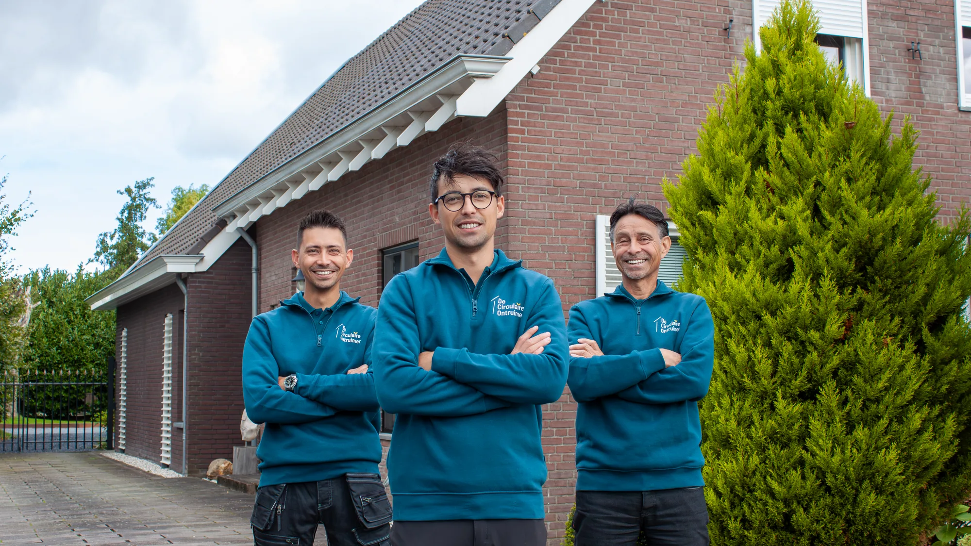 Drie medewerkers van De Circulaire Ontruimer in bedrijfskleding voor een woning