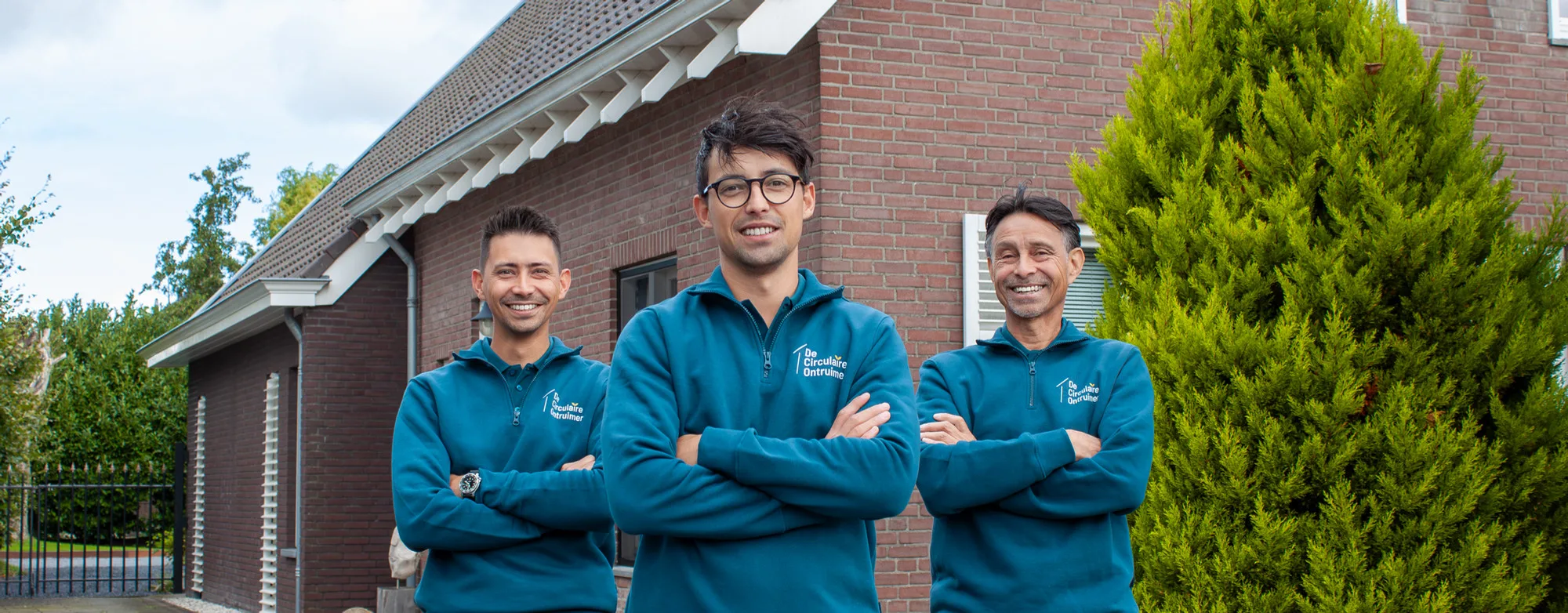 De drie medewerkers van De Circulaire Ontruimer in blauwe polo's voor een woning