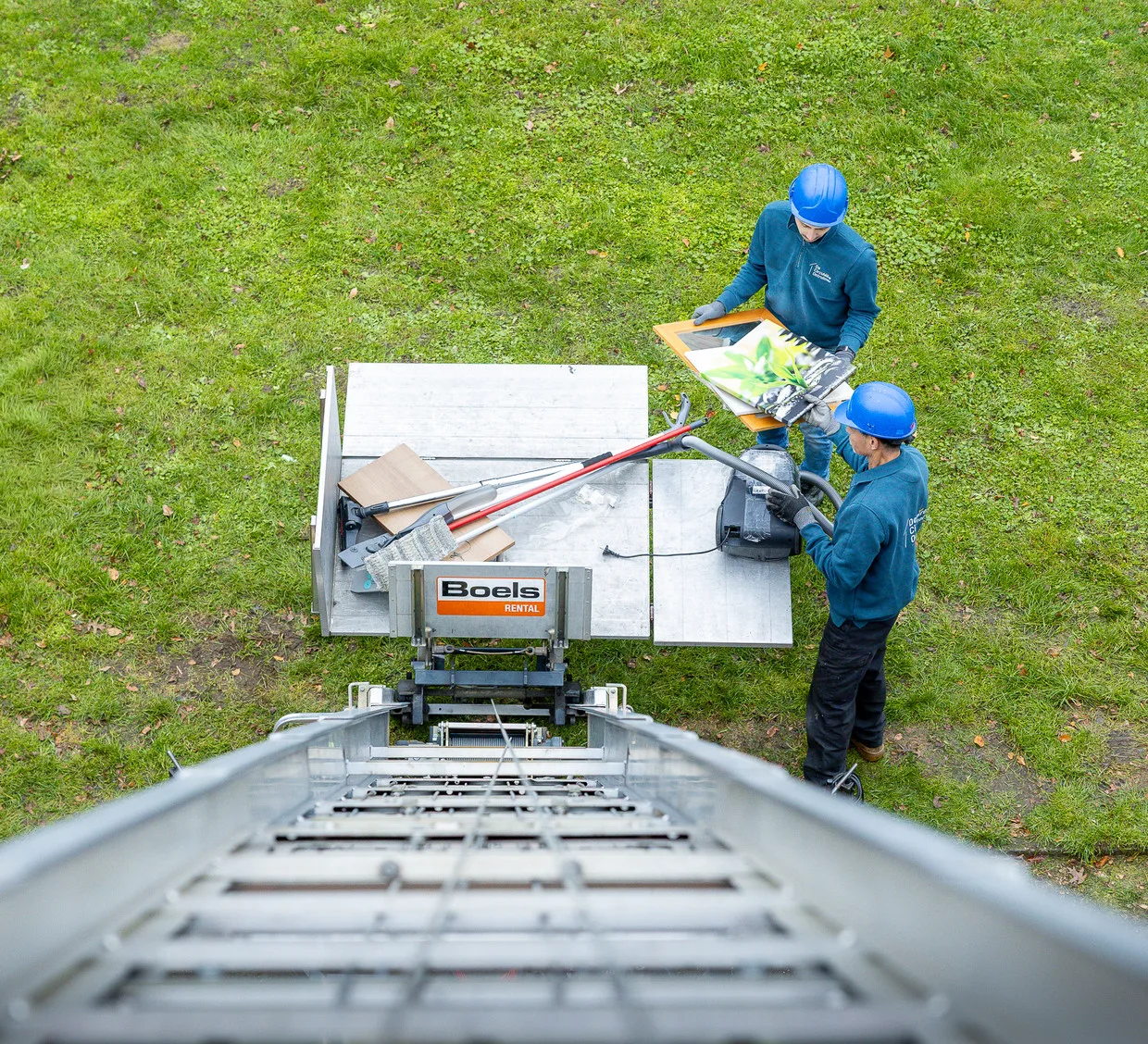 Twee medewerkers van De Circulaire Ontruimer laden spullen uit een woning in een verhuislift